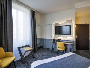 a hotel room with a bed and a desk and a television at Hôtel Mercure Rodez Cathédrale in Rodez