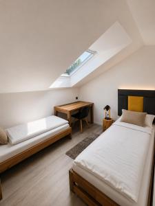 a attic bedroom with two beds and a desk at Apartmány Panorama Harrachov in Harrachov