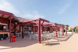 a restaurant with tables and chairs under a roof at Villa du Lac - Conciergerieland in Soustons