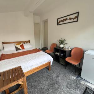 a bedroom with a bed and two orange chairs at Rizvi house in Moston