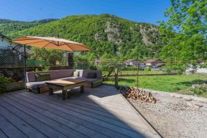 a wooden deck with a table and an umbrella at Gite - La grange Tima in Orgeix