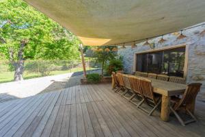 a wooden deck with a wooden table and chairs at Gite - La grange Tima in Orgeix