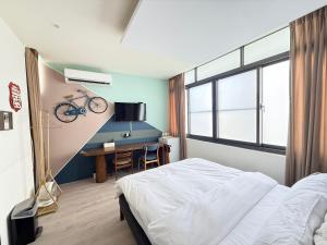 a bedroom with a bed and a desk with a bike on the wall at 會呼吸的房-採自助式入住-有電梯 in Huwei