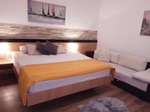 a bedroom with a large bed and a couch at Apartman Lovrić Đakovo in Đakovo