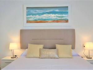a bedroom with a white bed with a painting above it at La perla del mar 1 in Son Servera