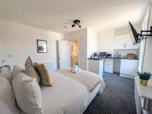 a bedroom with a white bed and a kitchen at The Marlowe in Southport