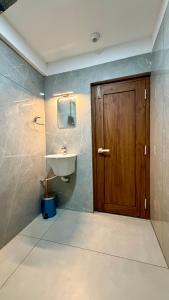 a bathroom with a sink and a wooden door at TCS SUITES Chala Bypass Kannur in Thottada +15 photos