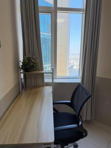 a desk and a chair in a room with a window at Spacious and Calm in Ajman 
