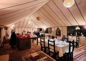 a dining room with tables and people in a tent at Palace desert camp in Merzouga