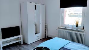 a bedroom with a bed and a television and a window at Geesthaus Geestland in Geestland