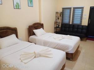 two beds in a hotel room with bows on them at Limlay House in Ban Suan On
