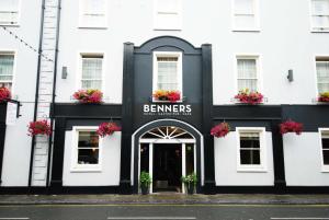 ein schwarzweißes Gebäude mit Blumen in der Tür in der Unterkunft Tralee Benners Hotel in Tralee