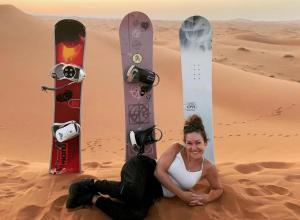 a woman sitting in the desert with two snowboards at Palace desert camp in Merzouga
