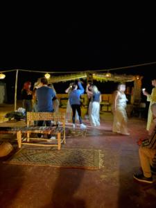 a group of people standing around a wedding party at Palace desert camp in Merzouga
