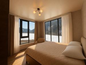 a bedroom with a large bed and large windows at Villa Tba near Borjomi, Tsemi and Sadgeri in Tsemi