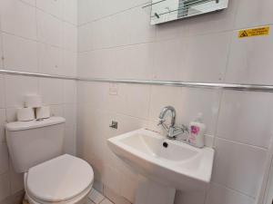 a white bathroom with a toilet and a sink at The Forest- Greenwood in Cambridge