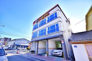 a white building with blue windows on a street at Sokcho otwohouse pension in Sokcho