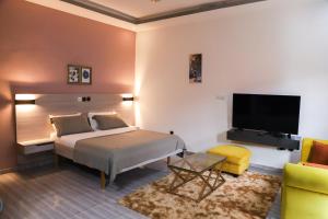 a bedroom with a bed and a tv and a couch at Résidences AMAN in Morofé