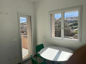 a white table and chairs in a room with two windows at Domus Palatium in Palazzolo Acreide