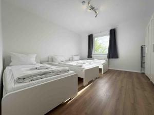 two beds in a white room with a window at LEU111 komfortable Monteurwohnung in Leuchtenberg +2 photos
