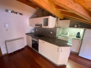 a kitchen with white cabinets and a counter top at Ático Seijas 6 in Tui
