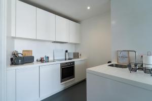 a white kitchen with white cabinets and a sink at THE OLIVE SUITE At The Rotunda in Birmingham