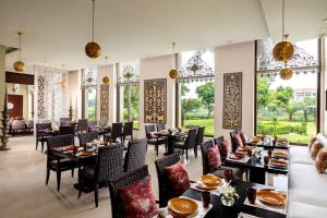 a restaurant with tables and chairs and windows at Jaypee Greens Golf and Spa Resort in Greater Noida