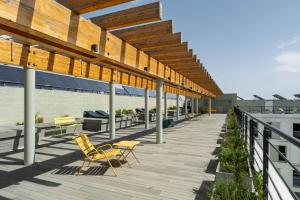 a deck with chairs and tables on a building at Codomo Living Carcavelos Lombos in Carcavelos