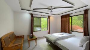 a bedroom with a bed and a chair and windows at EYE VIEW hotel skardu in Skardu