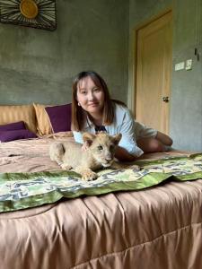 a girl sitting on a bed with a baby lion cub at Lion Cafe Resort in Ban Huai Sieo
