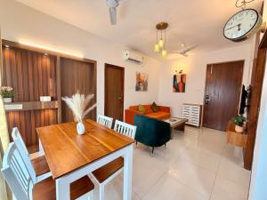 a dining room and living room with a table and a clock at Bay Breeze 2BR Apt Amoret Homes in Chicalim