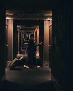 Eine Frau, die mit einem Koffer einen Flur entlanggeht. in der Unterkunft Arctic City Hotel in Rovaniemi