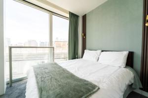 a bedroom with a white bed with a large window at THE OLIVE SUITE At The Rotunda in Birmingham