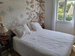 a bed with white sheets and pillows in a bedroom at La Petite Bergerie in Fréjus