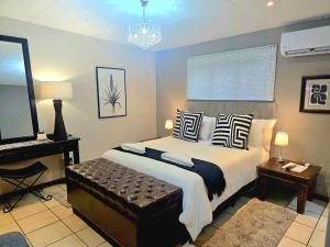 a bedroom with a large bed and a chandelier at The Lantern Guesthouse in Bloemfontein +14 photos