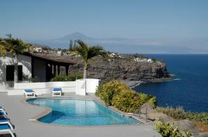a swimming pool with chairs and a view of the ocean at Apartamentos Santa Ana - Adults Only in Playa de Santiago