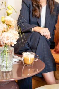 a woman in a suit sitting at a table with a cup of coffee at Hôtel de France in Monte Carlo +30 photos