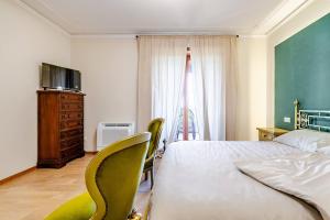 a bedroom with a bed and chairs and a television at Villa Zina in Pasiano di Pordenone