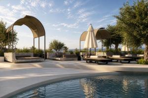a patio with a pool and umbrellas and a swimming pool at Mamay Hotel in Fira