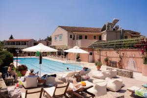 a pool with chairs and umbrellas next to a building at Garden Budget Rooms By Dominoes Corfu in Ipsos