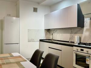 a kitchen with white cabinets and a table and chairs at Basarab Residence Urban Comfort Apartment in Râșcani in Chişinău