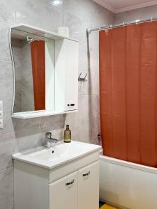 a bathroom with a sink and a red shower curtain at Basarab Residence Urban Comfort Apartment in Râșcani in Chişinău