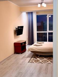 a bedroom with a bed and a tv and a window at Basarab Residence Urban Comfort Apartment in Râșcani in Chişinău