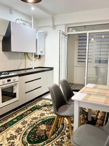 a kitchen with white cabinets and a table and chairs at Basarab Residence Urban Comfort Apartment in Râșcani in Chişinău +8 photos