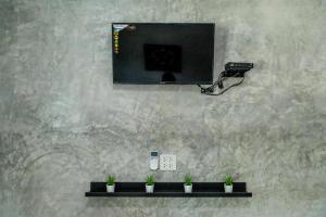 a television on a wall with plants on a shelf at Sun Resort in Sa Kaeo