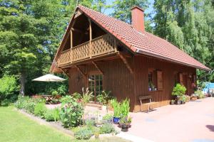 una pequeña casa de madera con sombrilla y algunas flores en Anglo-Polish Holidays, en Chycina