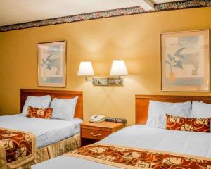 a hotel room with two beds and a phone at Rodeway Inn Kalkaska in Kalkaska