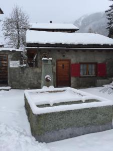 a house covered in snow in front of a building at Fravgia veglia in Andeer