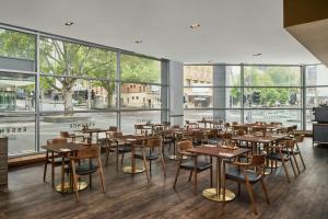 ein Restaurant mit Tischen und Stühlen und großen Fenstern in der Unterkunft Melbourne Marriott Hotel in Melbourne