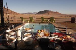a table with food next to a swimming pool at Greenfire Desert Lodge in Maltahöhe